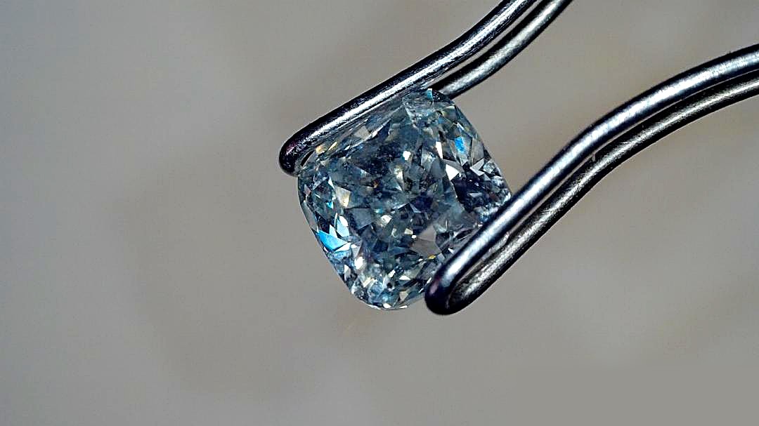 Blue cushion-cut diamond, held in tweezers